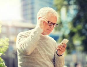 Senior Cell Phone Addiction: senior man texting message on smartphone in city