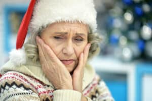 Portrait of sad senior woman in Santa hat isolated on white background - senior holiday mental health