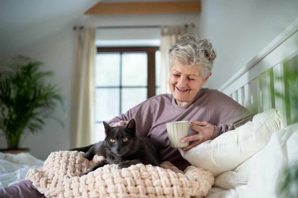 A senior woman smiling and practicing self care with her pet cat and Seniors Helping Seniors In-Home Senior Care Services in southwest Broward County Florida.