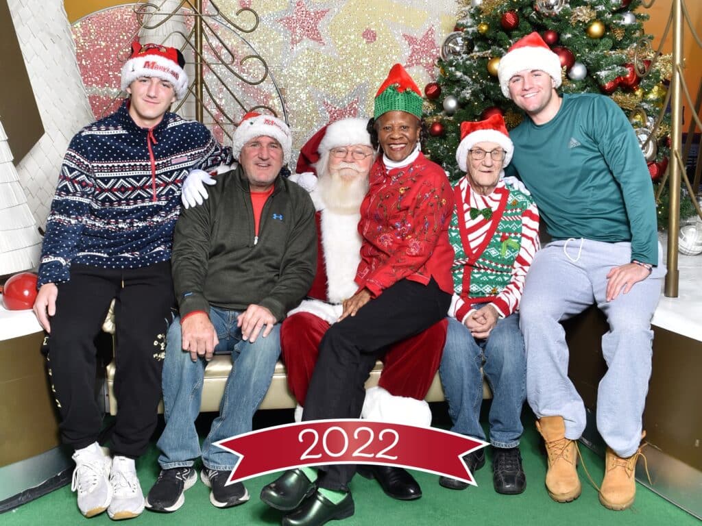 A Christmas card depicting a family posing with Santa Clause and a Seniors Helping Seniors caregiver. Photo taken in the greater Potomac area.